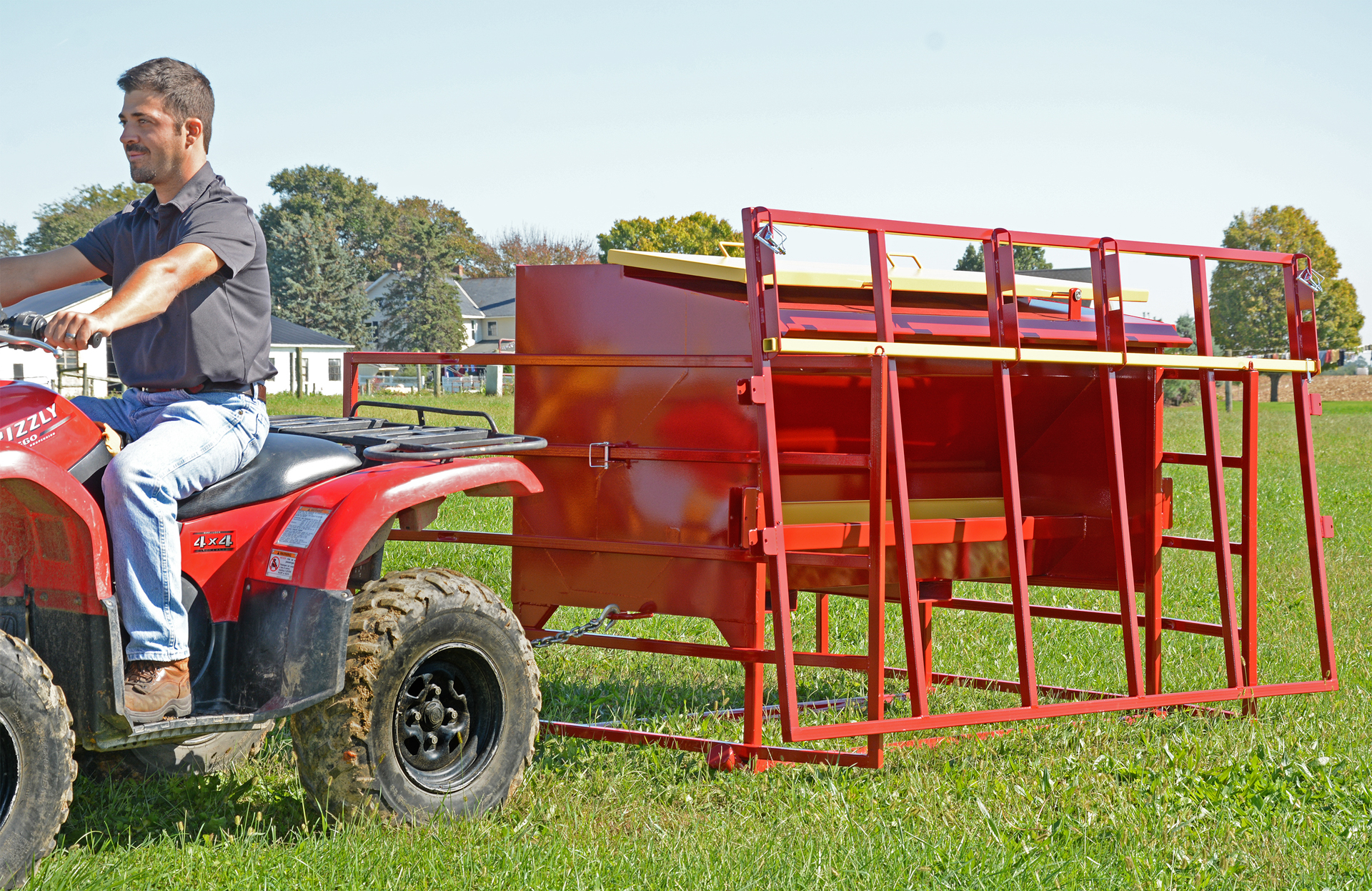 front view of man pulling calf creep feeder on four wheeler